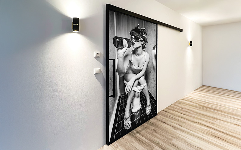 Erkelenz Stahl Lofttür als Schiebetür mit einem Motiv bedruckt. Ansicht in einem Flur.